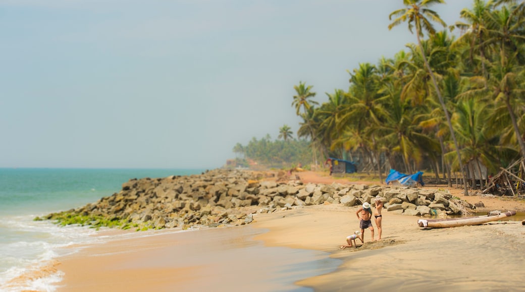 A family of 2 parents and a girl are relaxing on a empty tropical beach in the Kerala state, India.