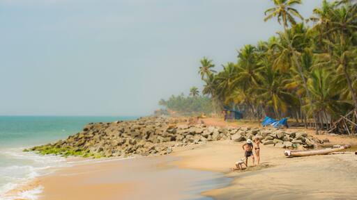 A family of 2 parents and a girl are relaxing on a empty tropical beach in the Kerala state, India.