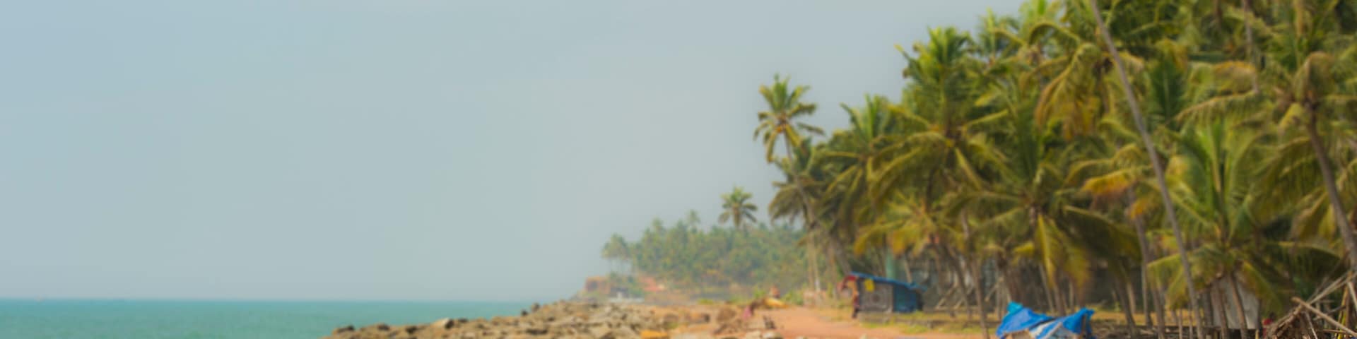A family of 2 parents and a girl are relaxing on a empty tropical beach in the Kerala state, India.