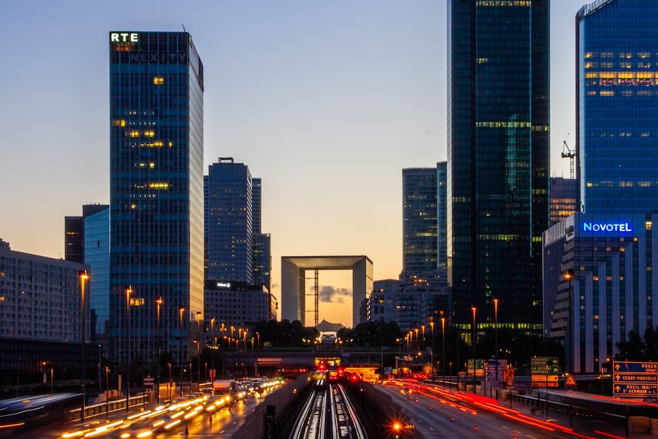 A cityscape with tall buildings, including RTE and Novotel, and a busy highway with light trails.