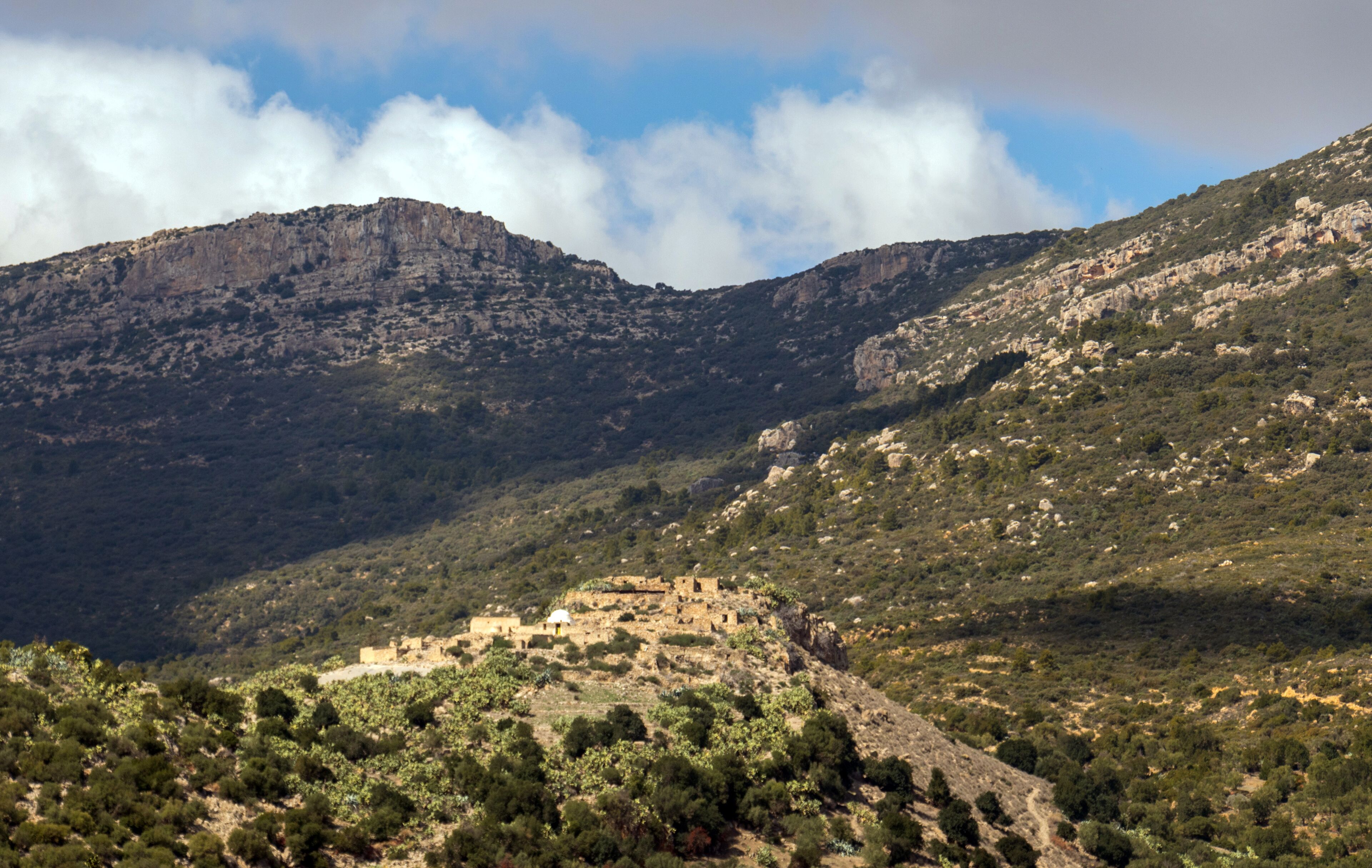 A mountainous landscape with a small village nestled among rocky hills and sparse vegetation.
