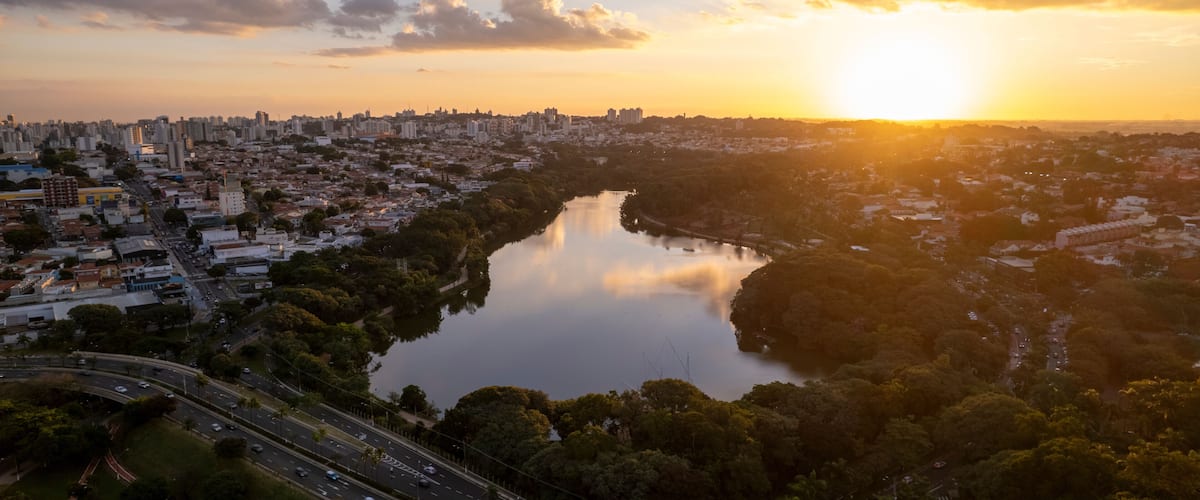 Paisagem urbana com rio, ponte e pôr do sol.
