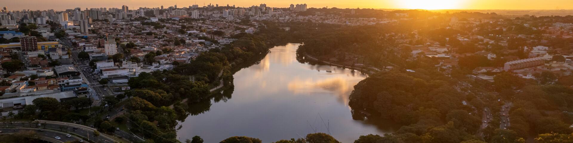 A cityscape with a river, a bridge, and a sunset.
