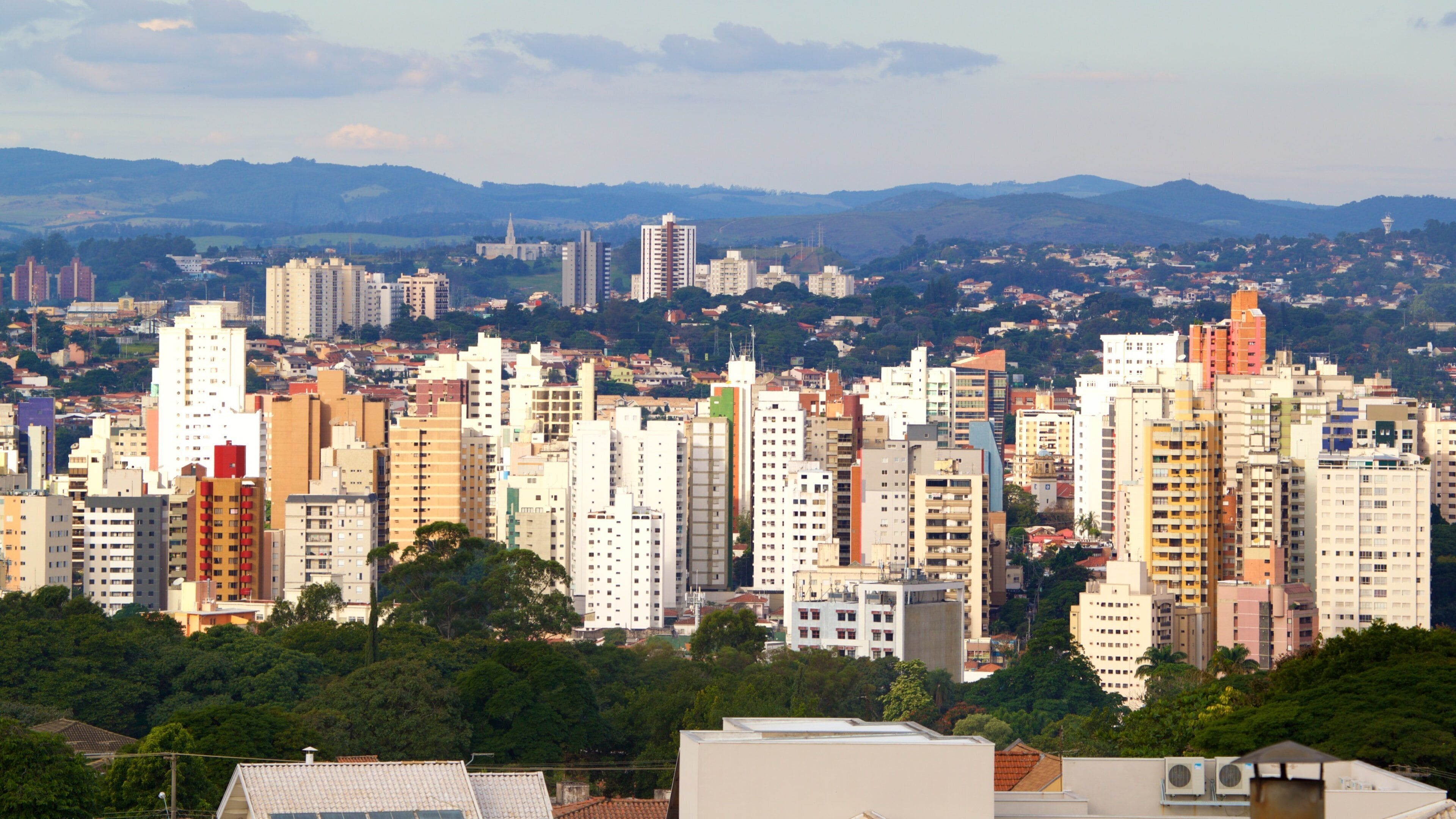 Un paisaje urbano con numerosos edificios altos, una iglesia destacada y colinas onduladas al fondo.