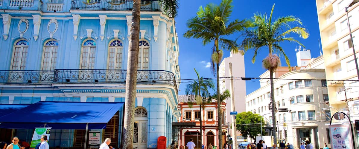 A historic building with blue and white architecture, palm trees, and people walking on the sidewalk.