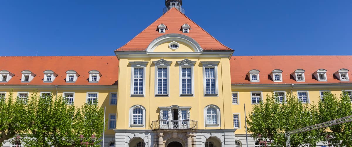 A yellow building with a red roof and a tower.