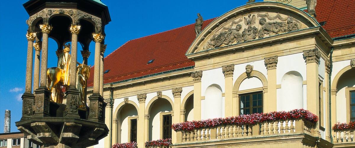 A historic building with a red-tiled roof, ornate columns, and a clock tower.