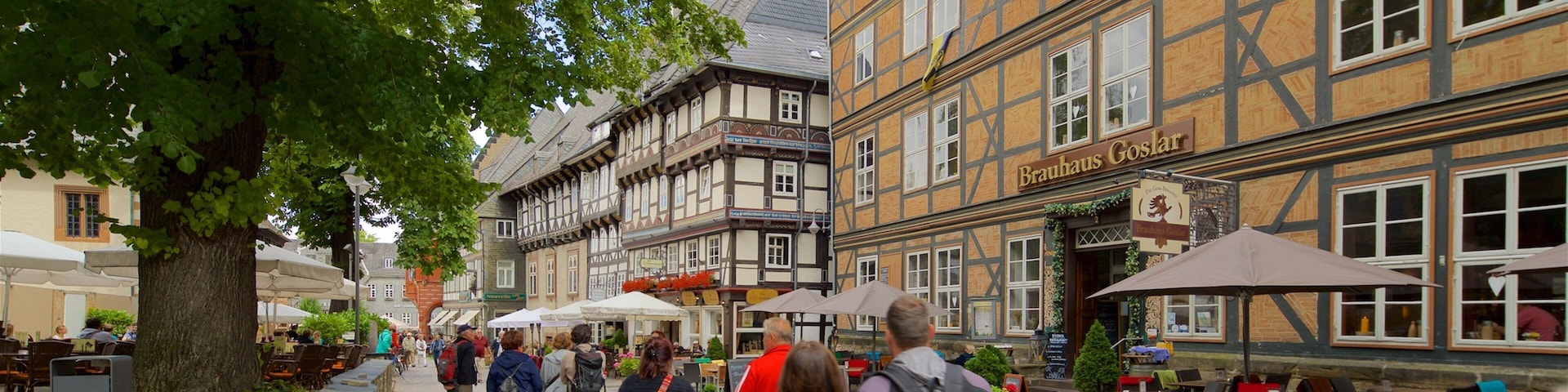 Eine Kopfsteinpflasterstraße gesäumt von traditionellen Fachwerkhäusern und Außenbereichen mit Sitzgelegenheiten.