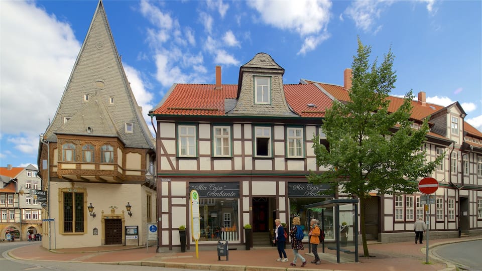 A traditional European town with half-timbered houses, a church with a pointed steeple, and a bus stop.