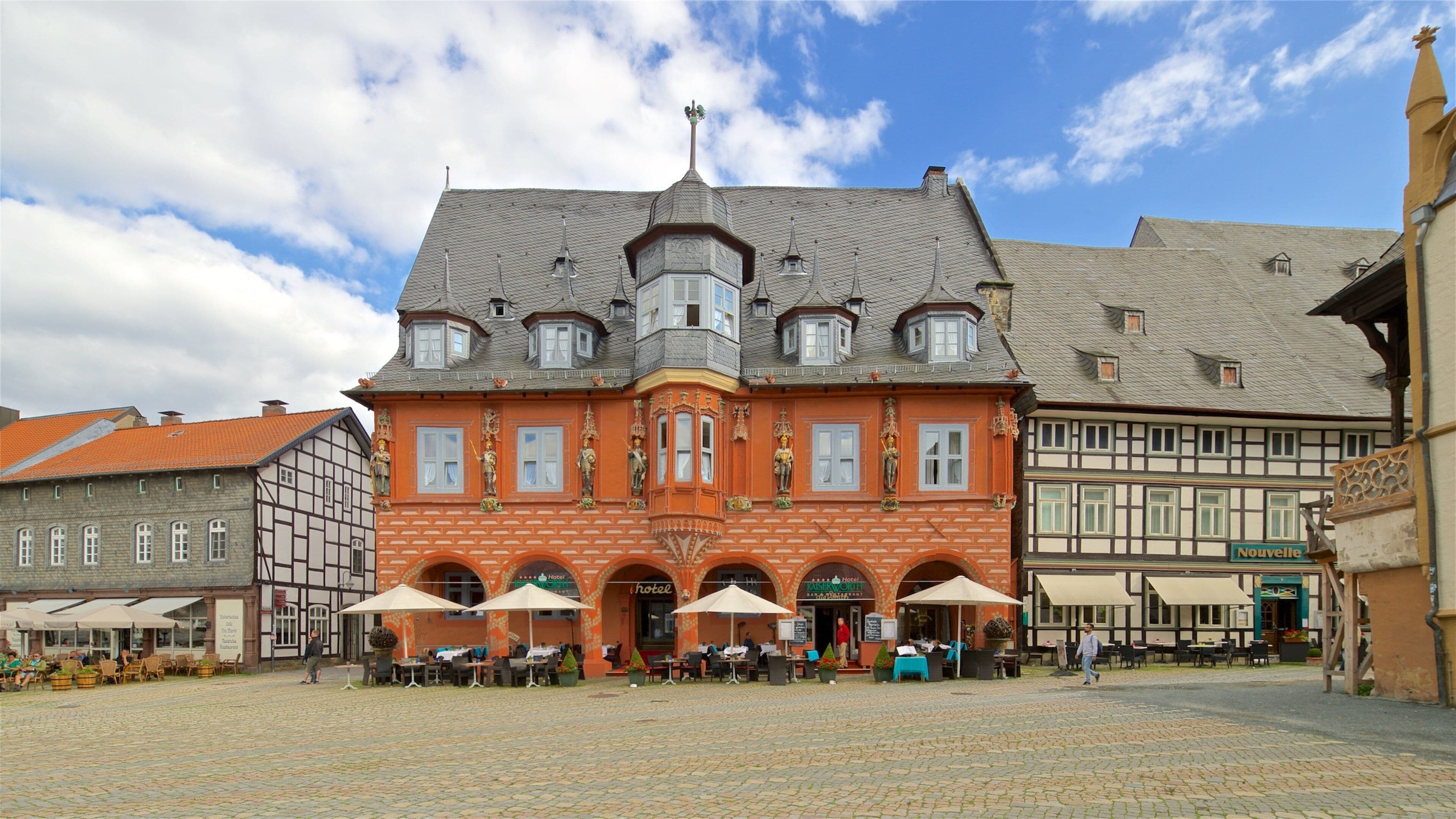 Um edifício histórico com arquitetura ornamentada e uma praça de paralelepípedos.