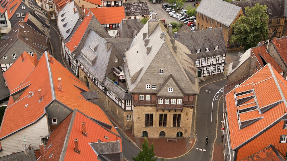 Eine historische Stadt mit roten Ziegeldächern, einem markanten Kirchengebäude mit hohem Glockenturm und engen Kopfsteinpflasterstraßen.