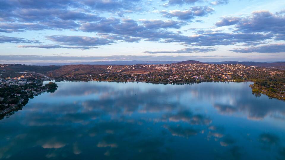 A lake surrounded by a town with mountains in the background.