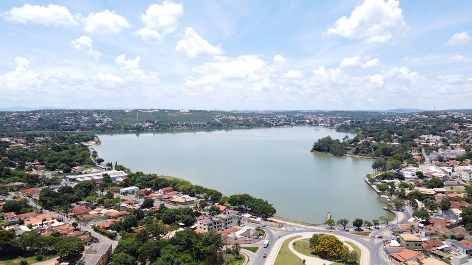 A lake surrounded by residential areas with red-roofed houses and a bridge crossing the water.