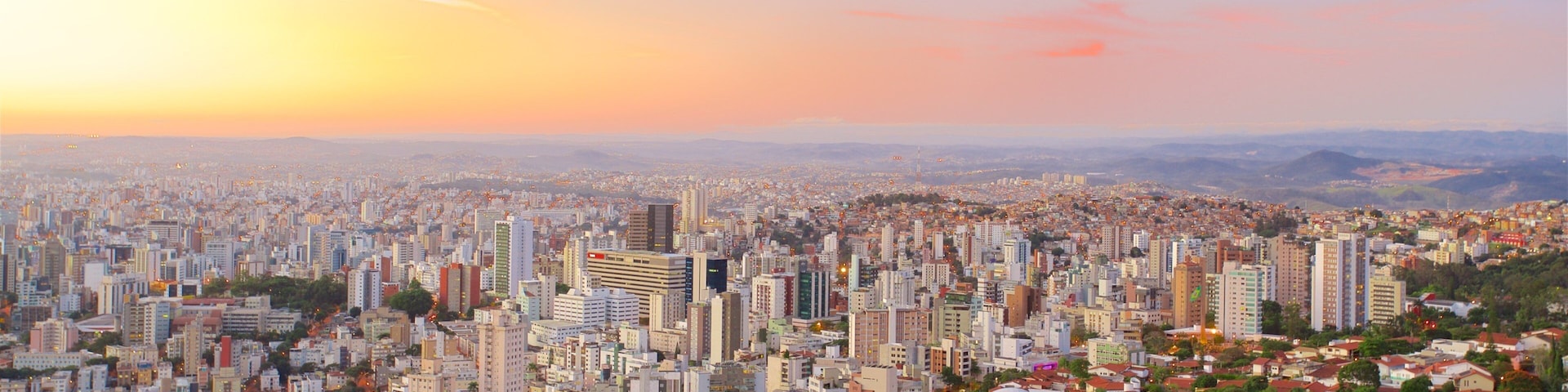 A cityscape at sunset with a mix of high-rise buildings and residential areas.