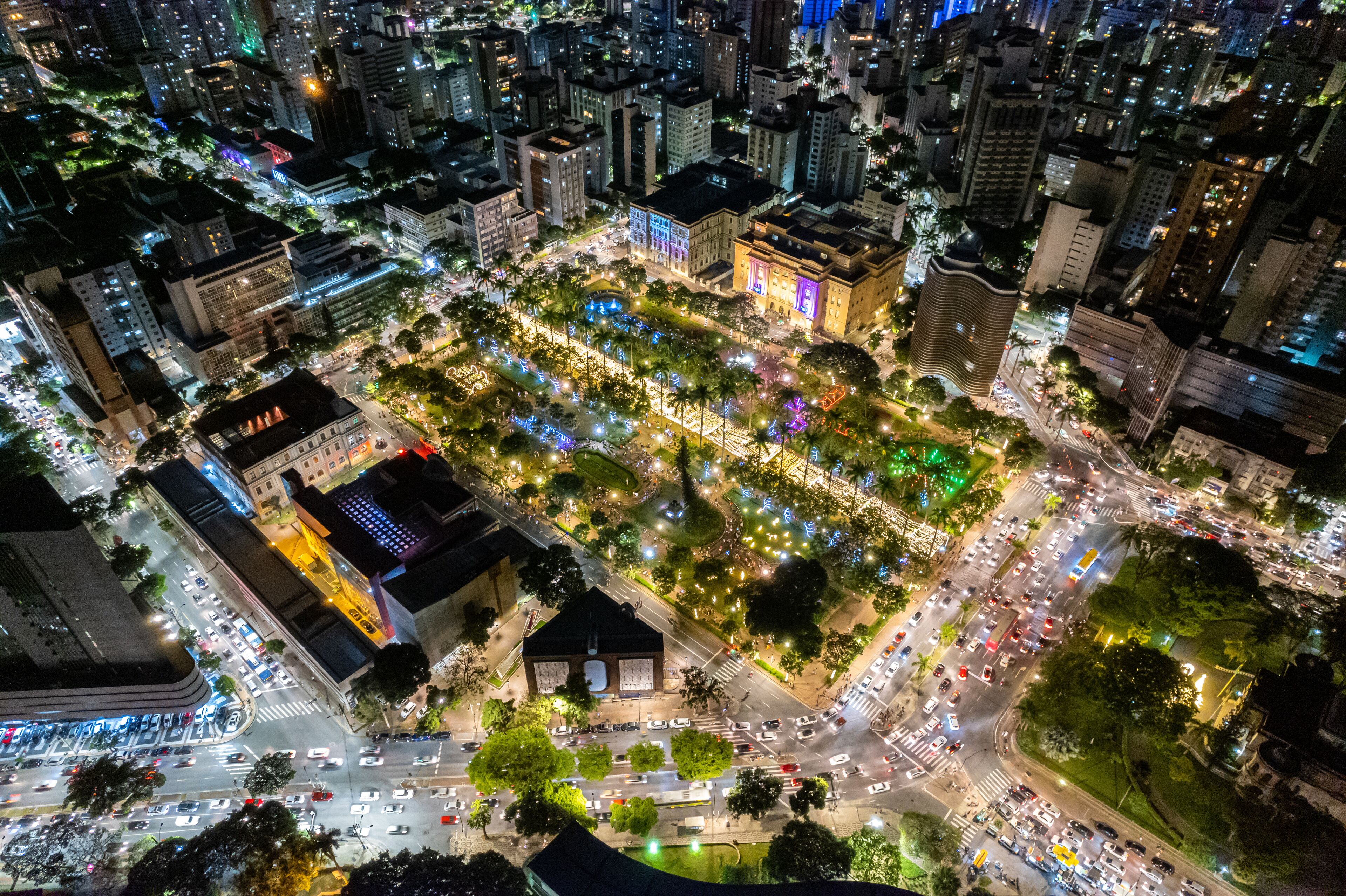 Luftaufnahme einer beleuchteten Stadt bei Nacht mit Straßen, Gebäuden und einem Park.