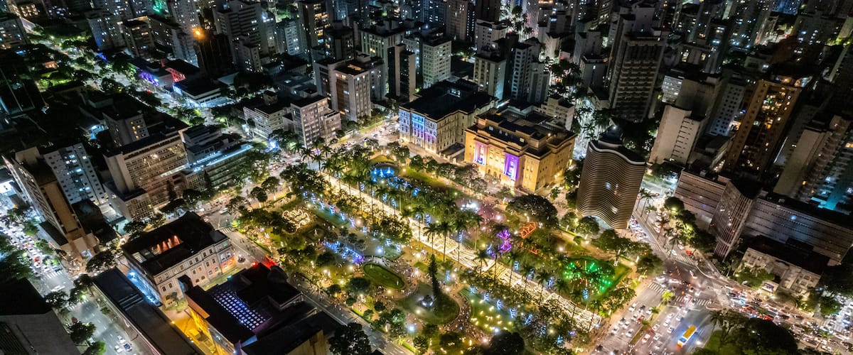 Una vista aerea di un paesaggio urbano notturno, con strade, edifici e un’area verde illuminati.