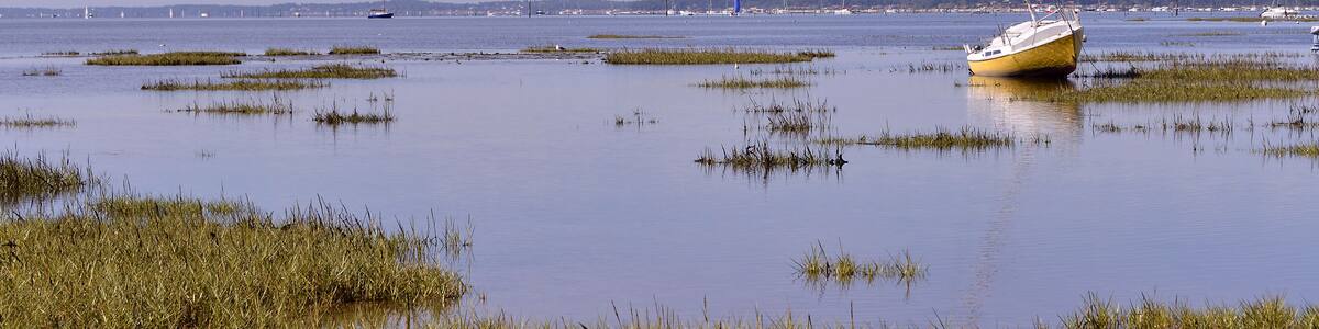 Sailboat at low tide at Arès, ostreicole commune located on shore of Arcachon Bay, in the Gironde department in southwestern France.
