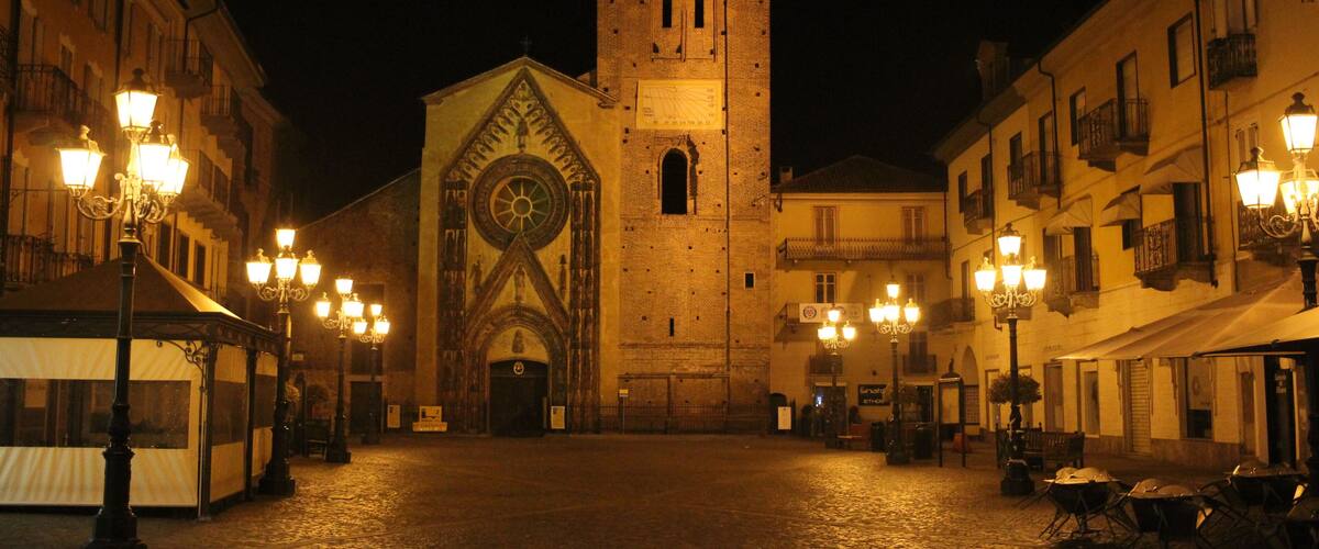 A historic square with a prominent clock tower, cobblestone streets, and ornate street lamps.