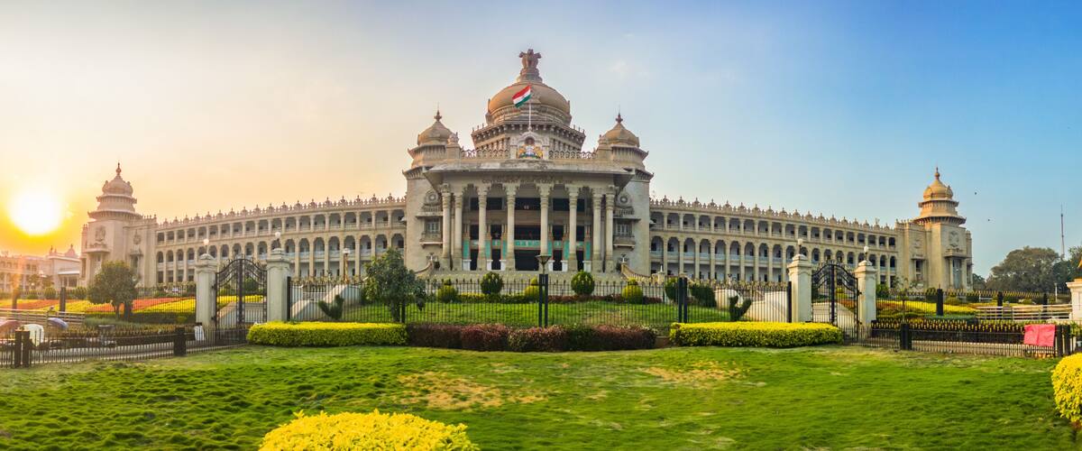 A large, ornate building with domed roofs and a central clock tower, surrounded by well-manicured gardens and statues.