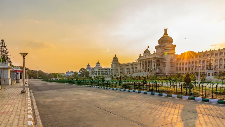 A grand building with domes and a large statue, surrounded by a fence and trees.