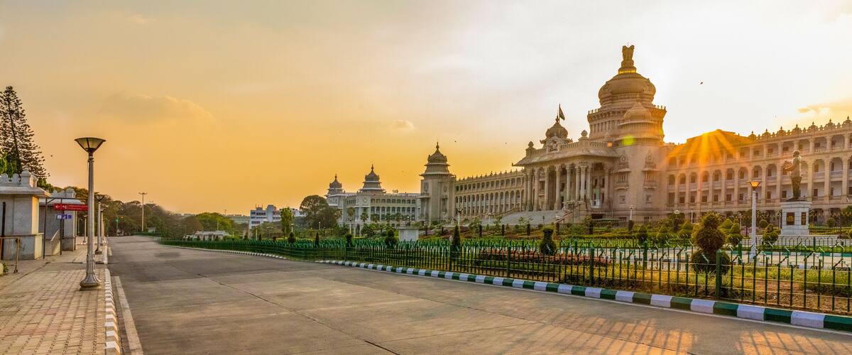 A grand building with domes and a large statue, surrounded by a fence and trees.