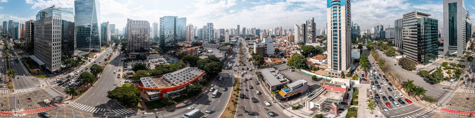 A cityscape with modern high-rise buildings, a curved road, and a mix of greenery.