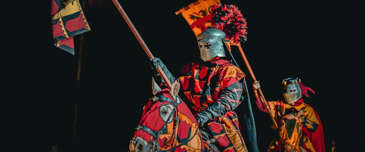 Two armored figures on horseback, one holding a flag.