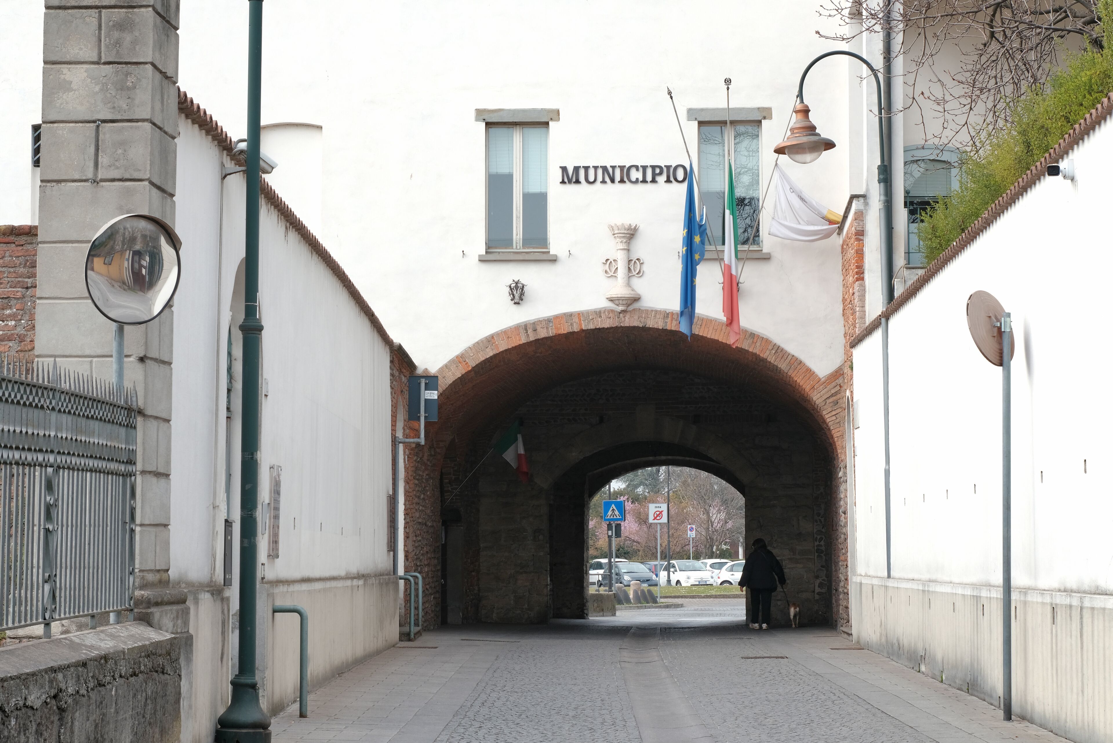 A pedestrian tunnel with a brick archway, a street lamp, and a sign that reads "MUNICIPIO".
