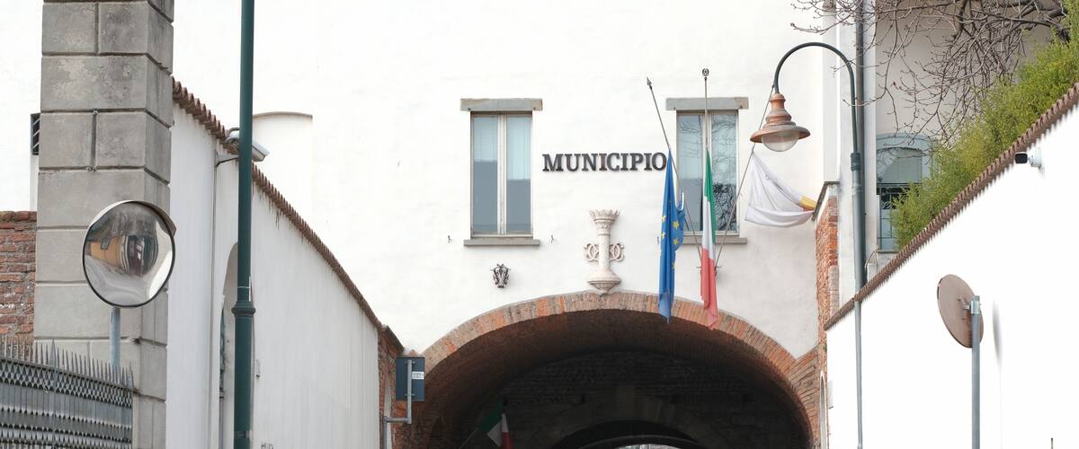 A pedestrian tunnel with a brick archway, a street lamp, and a sign that reads "MUNICIPIO".