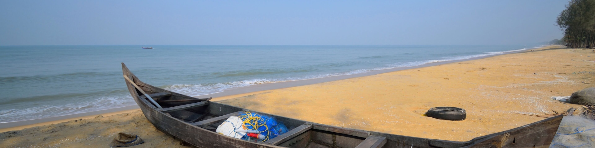 Un bote de madera en una playa arenosa, con el océano al fondo.