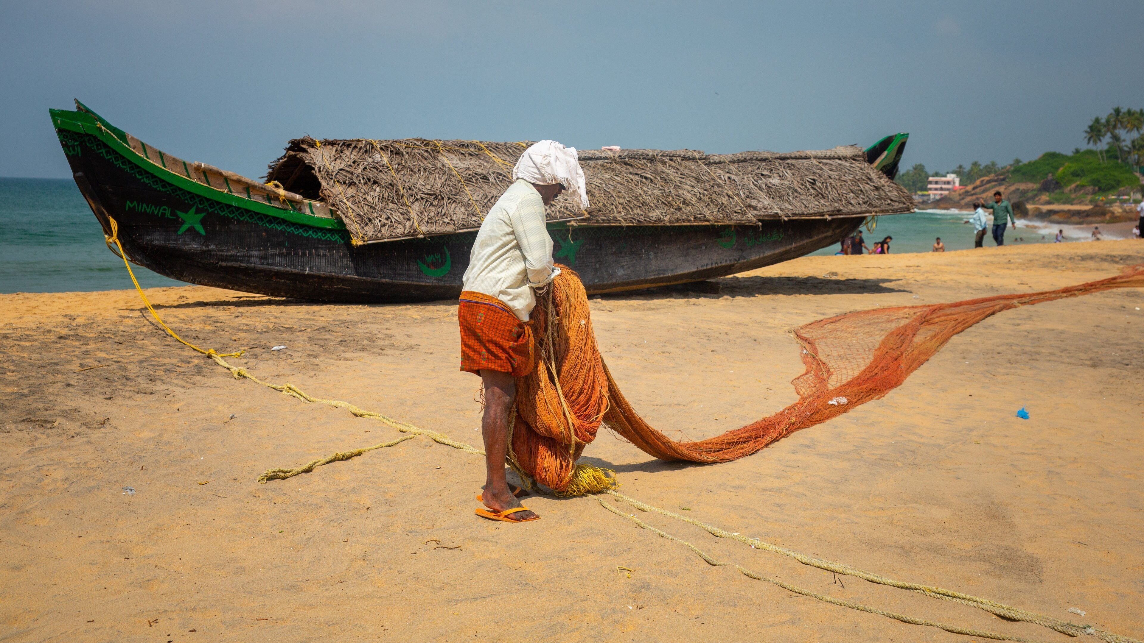 A man on a beach with a boat and fishing nets.
