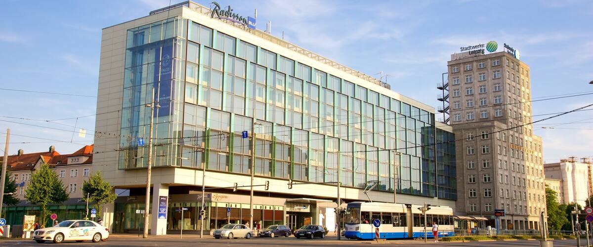 A modern building with large glass windows and a tram line in front.