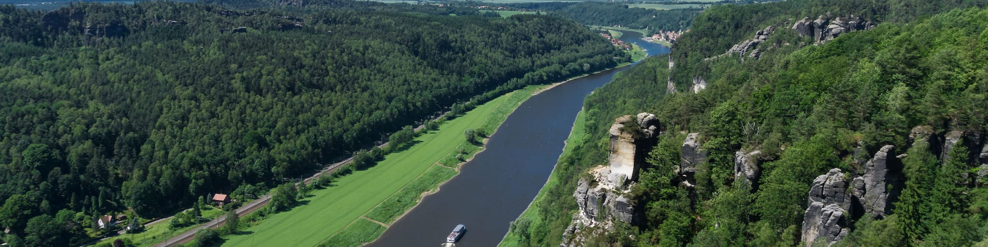 A river winding through a forested valley with rocky cliffs on one side.