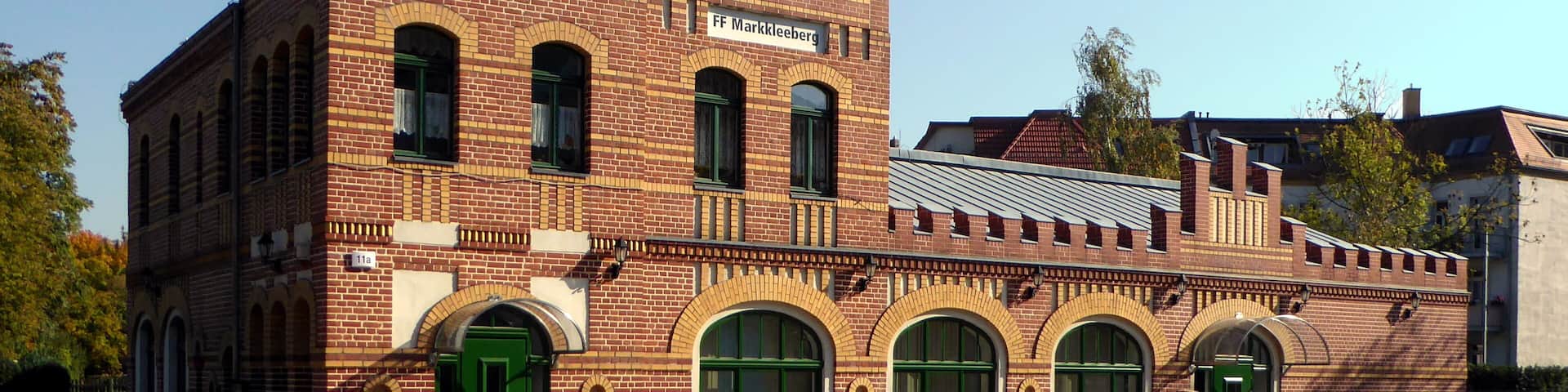 A historic brick building with a tower, arched windows, and a sign reading "FF Markkleeberg".