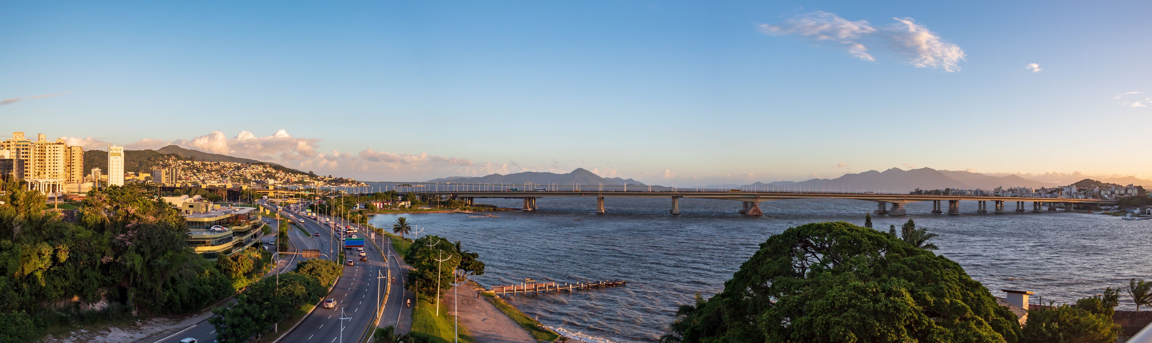 A cityscape with a river, a bridge, and mountains in the background.