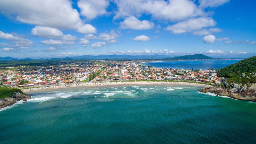 A coastal city with a beach, ocean, and mountains in the background.