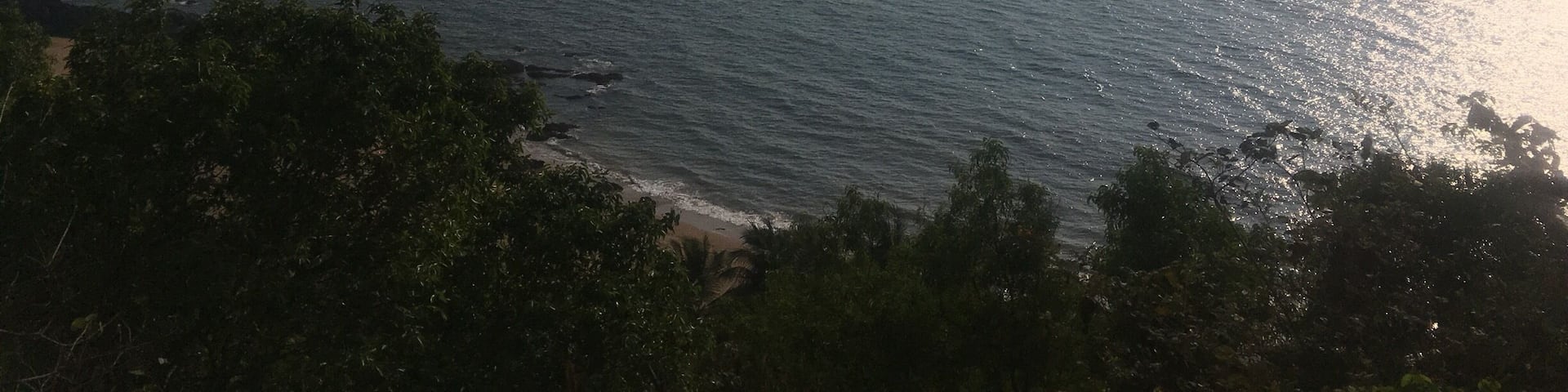 A coastal landscape with a beach, ocean, and distant landforms.