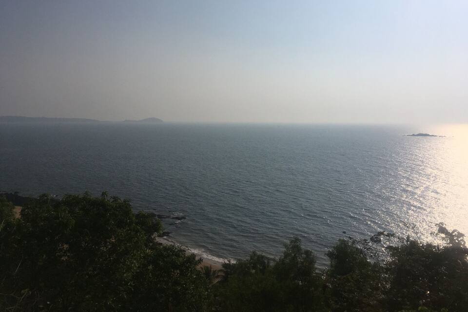 A coastal landscape with a beach, ocean, and distant landforms.
