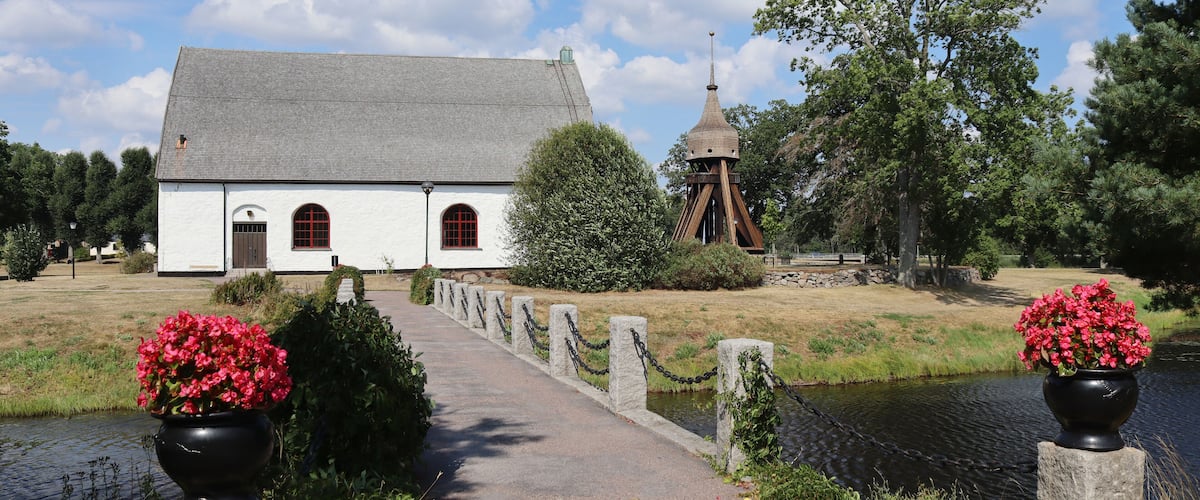 A white church with a bell tower, a pathway, and a canal.