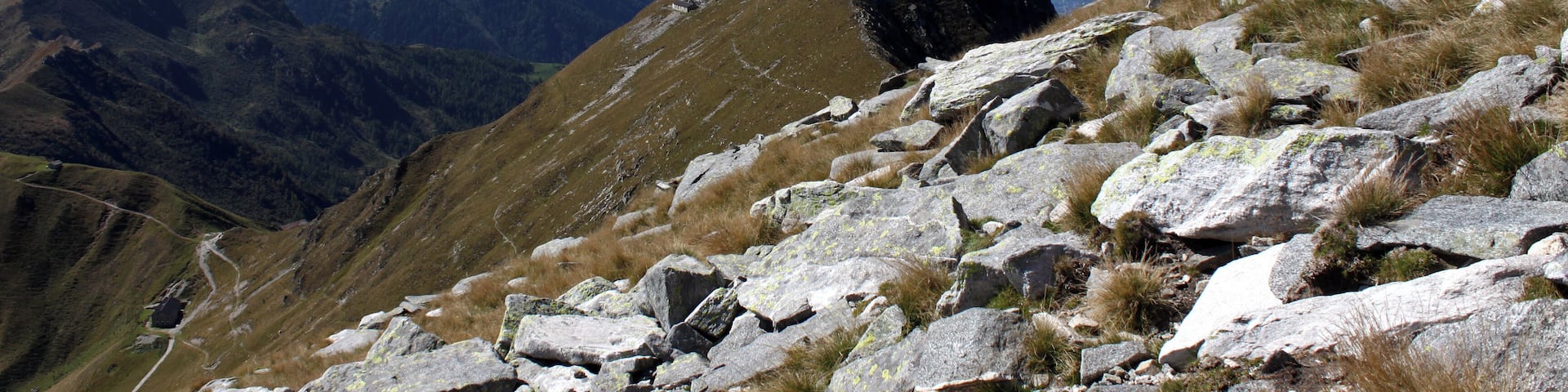An der Südflanke geht es Aufwärts zum Monte Marmontana ( 2316 m.ü.M.). Der Berg liegt genau im Grenzbereich zwischen der Schweiz und Italien. In der Bildmitte liegt der Cima di Cugn (2180 m.ü.M.) mit dem gleichnamigen Rifugio. Links unten ist der Passo San Jorio (2010 m.ü.M.), Grenzpunkt zwischen Italien und der Schweiz. In der Ferne ist der Lago Maggiore zu sehen.