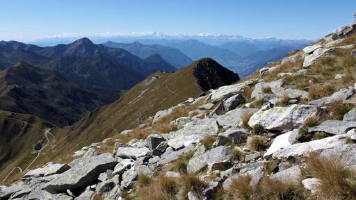 An der Südflanke geht es Aufwärts zum Monte Marmontana ( 2316 m.ü.M.). Der Berg liegt genau im Grenzbereich zwischen der Schweiz und Italien. In der Bildmitte liegt der Cima di Cugn (2180 m.ü.M.) mit dem gleichnamigen Rifugio. Links unten ist der Passo San Jorio (2010 m.ü.M.), Grenzpunkt zwischen Italien und der Schweiz. In der Ferne ist der Lago Maggiore zu sehen.