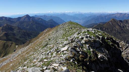 Auf dem Gipfel des Monte Marmontana ( 2316 m.ü.M.) über den genau die Grenze zwischen der Schweiz und Italien verläuft. Hier geht der Blick zum Passo San Jorio (2010 m.ü.M.) (links im Bild) und dann weiter zum Lago Maggiore bis zum mächtigen Monte Rosa.