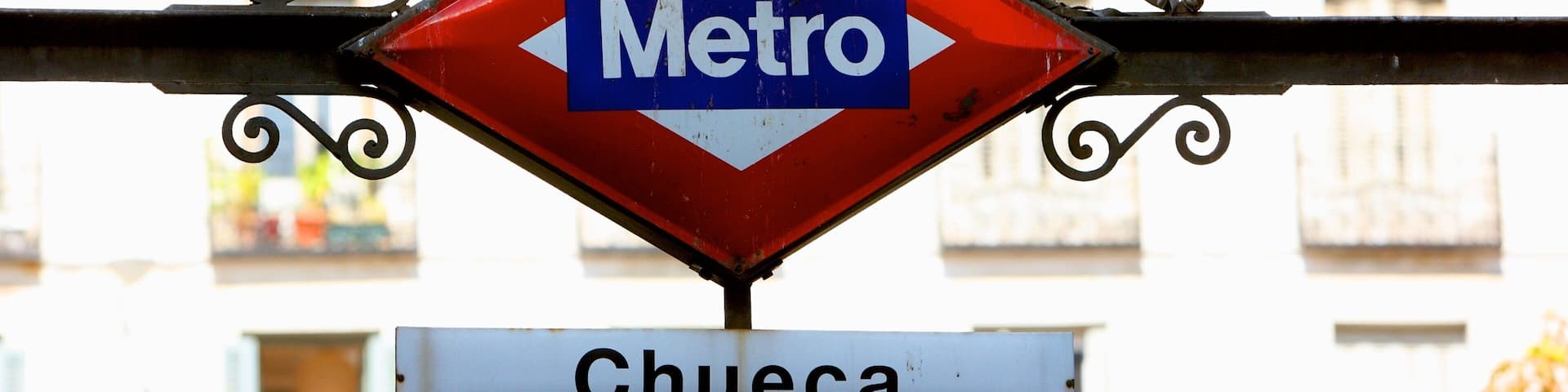 A red diamond-shaped sign with "Metro" and a white rectangular sign below it with "Chueca".