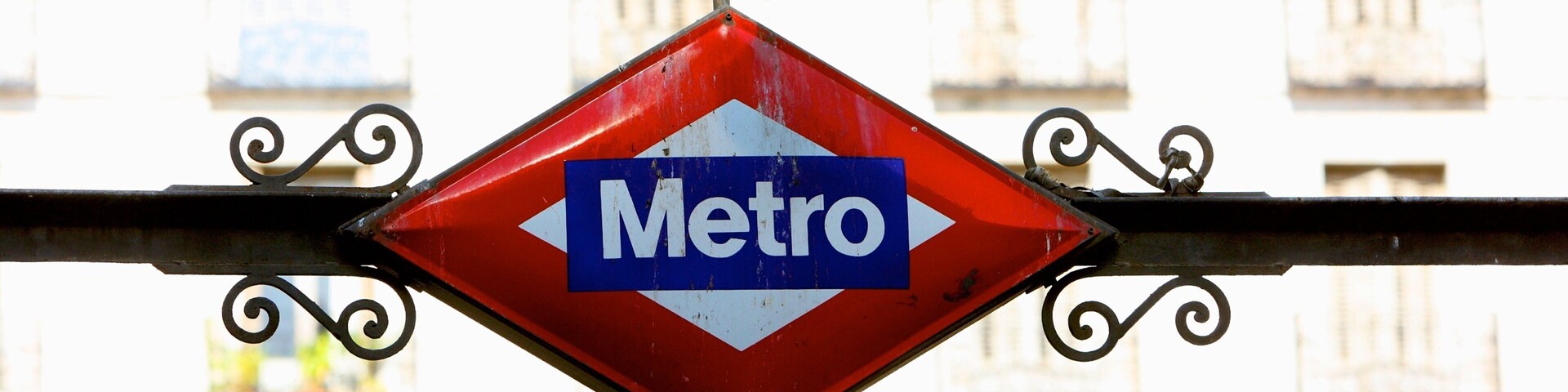 Una señal roja en forma de diamante con la palabra 'Metro' y una señal rectangular blanca debajo que dice 'Chueca'.