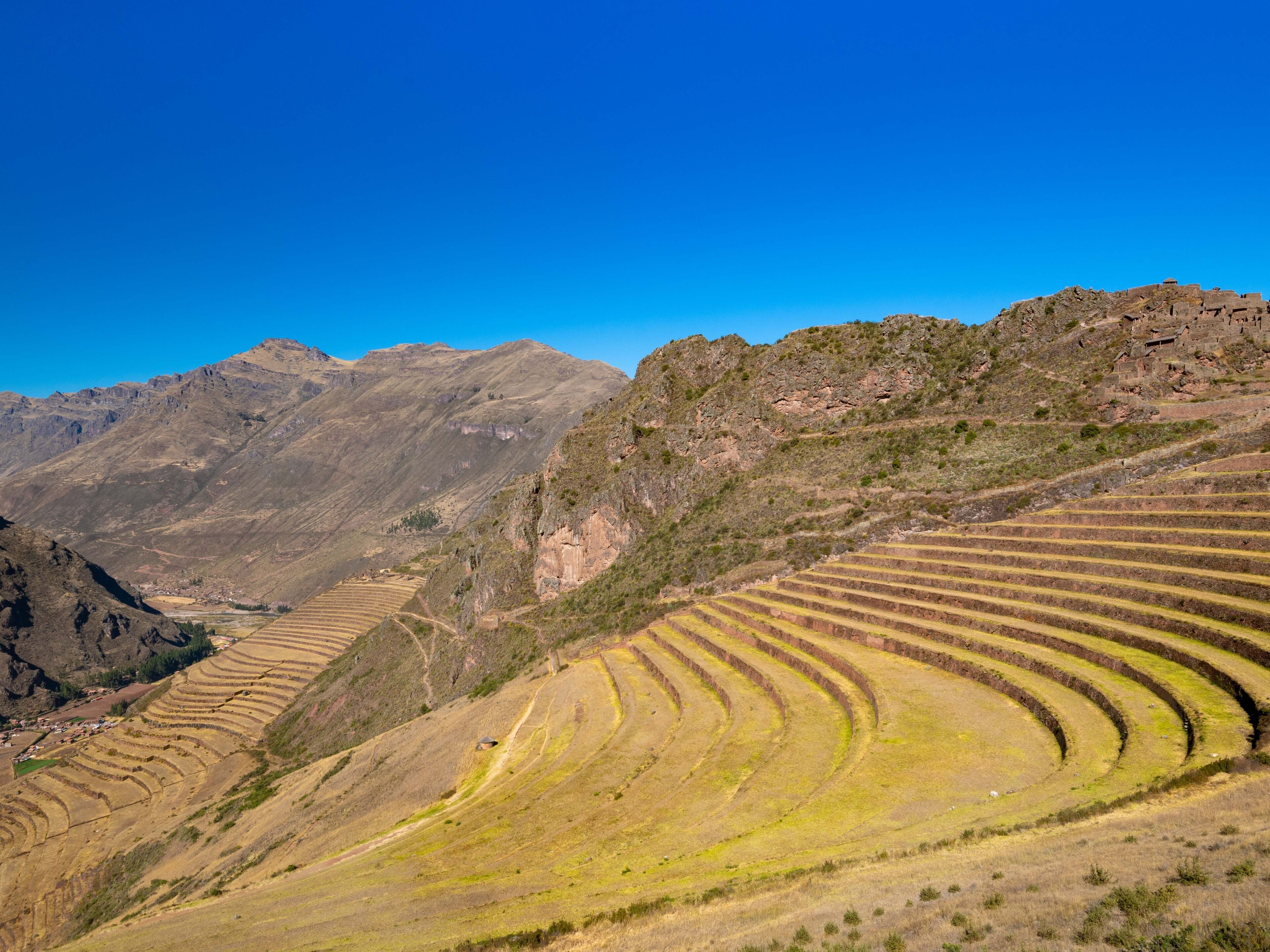 Terraced fields in a mountainous landscape with a clear blue sky.