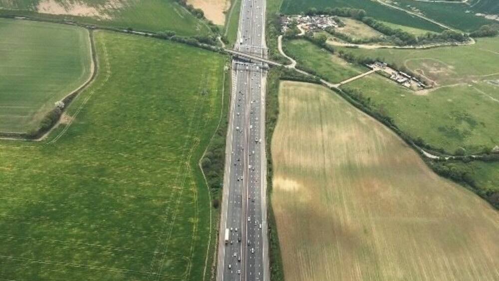 An aerial view of a highway with surrounding agricultural fields and a small settlement.