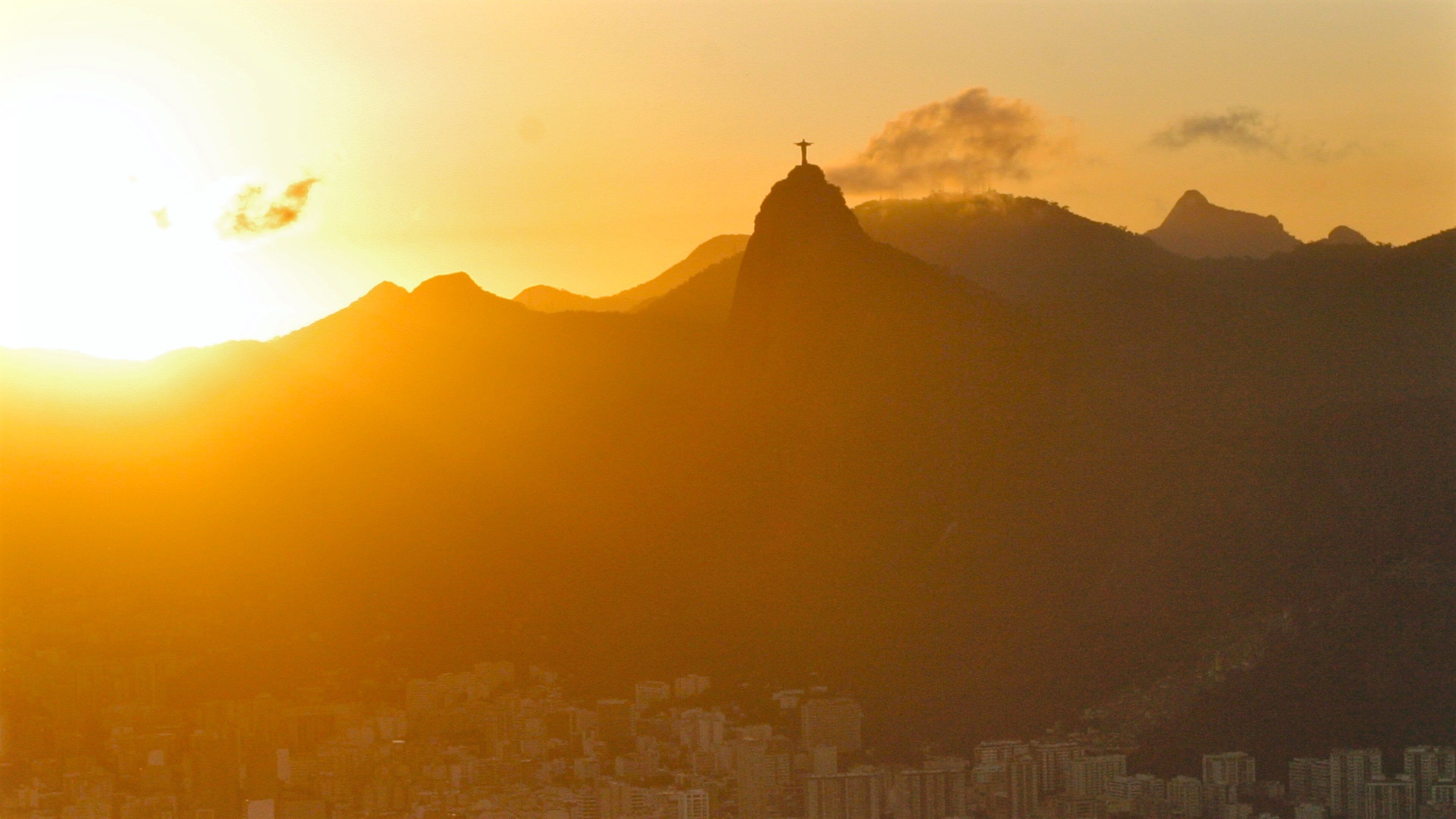 A cityscape with a prominent mountain and a cross on top, likely a landmark.