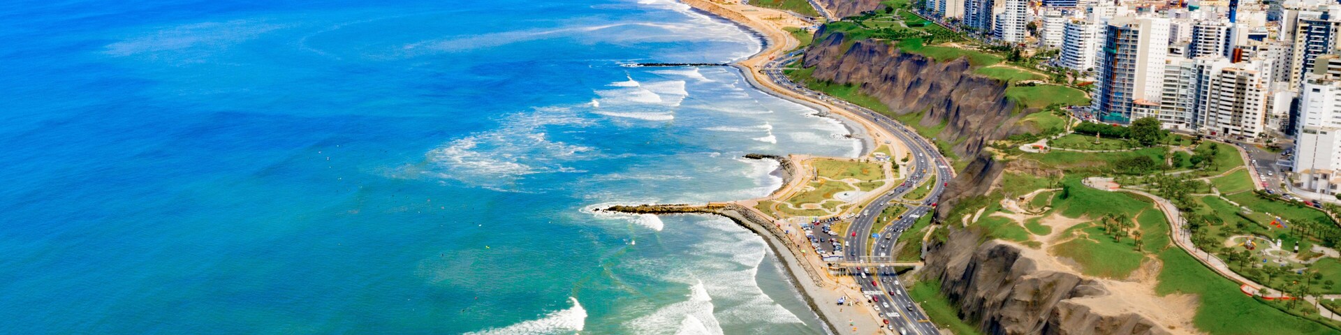 Un paisaje urbano costero con playa, acantilados y una autopista.