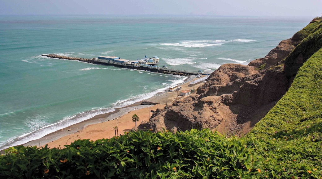The view of the coast and pier at Miraflores in Lima, Peru. There is a very nice paved walkway along the main avenue that has views over looking the coast and beaches for miles. The walkways pass through some well maintained parks and the popular Larcomar shopping mall. It is also common to see paragliders soaring above the cliffs in this area.