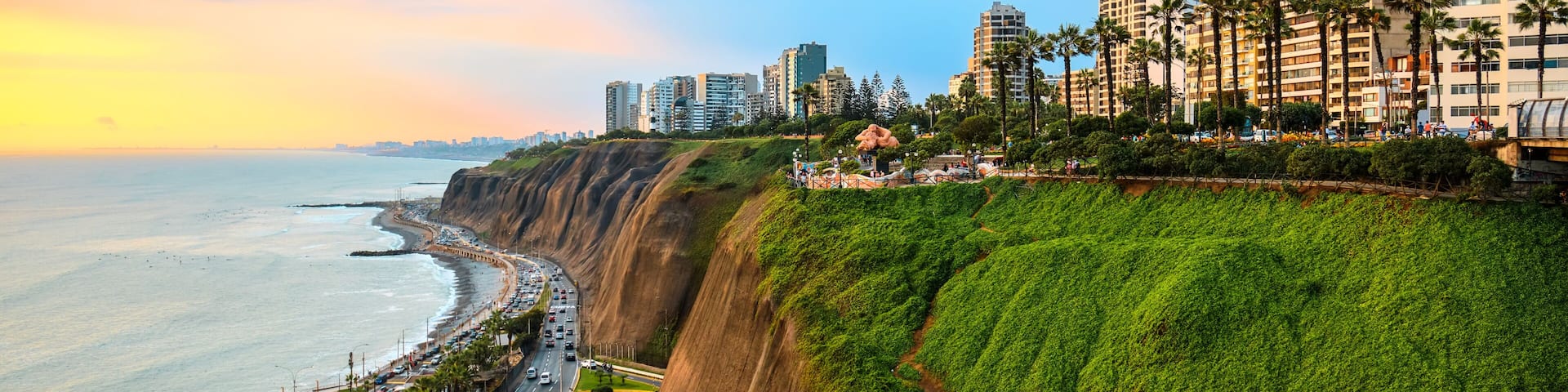 A coastal cityscape with a steep cliff, a beach, and a road running alongside the cliff.